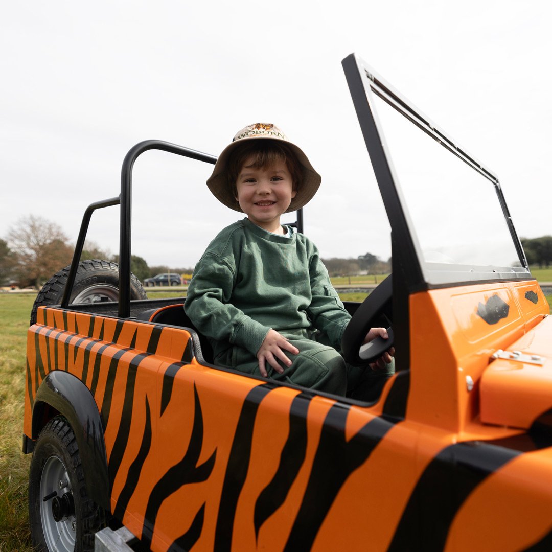 Small child driving a tiger striped mini Keeper vehicle