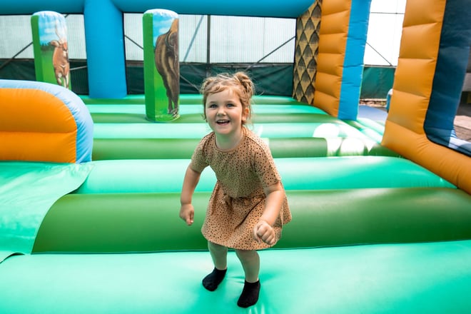 Little girl smiles as she bounces on bouncy castle 